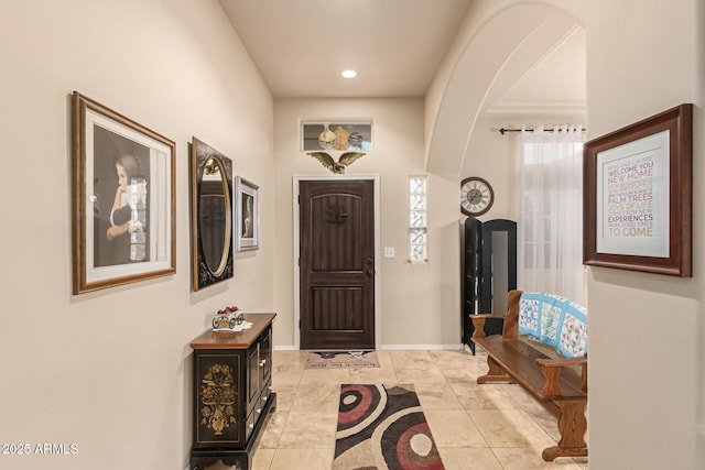 entrance foyer featuring light tile patterned floors, recessed lighting, arched walkways, and baseboards