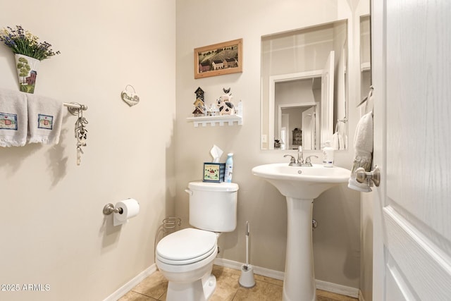 half bath with toilet, baseboards, and tile patterned floors