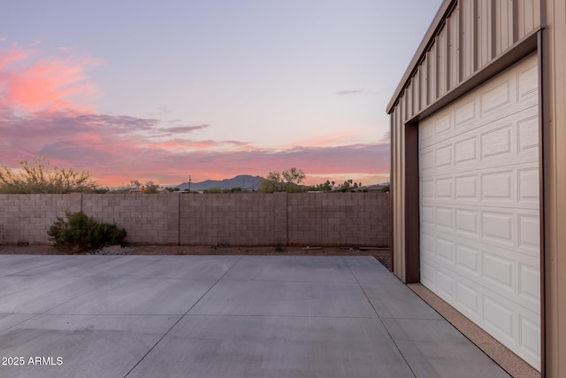 garage at dusk featuring fence and a mountain view