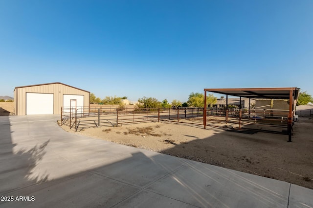 view of yard with an outbuilding, an exterior structure, a detached garage, and a rural view