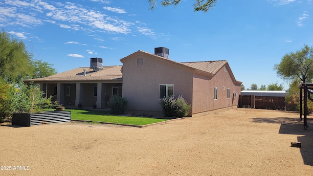 rear view of property with central air condition unit, fence, a tile roof, stucco siding, and a chimney