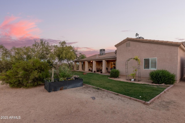 exterior space featuring a yard, a garden, stucco siding, and a patio