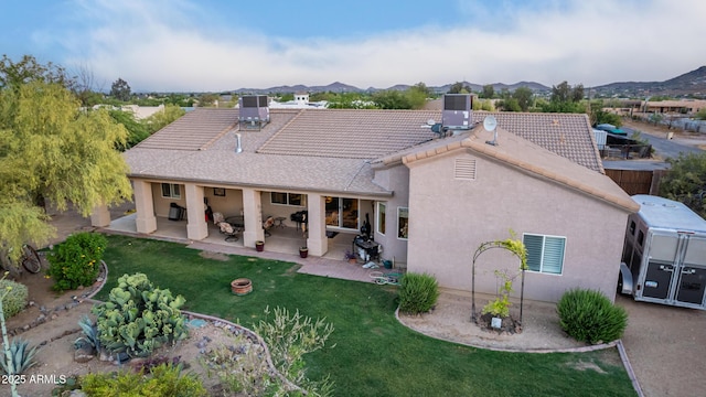 rear view of property featuring a patio area, central AC unit, stucco siding, and a yard