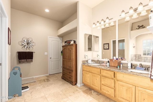 bathroom with tile patterned floors, a sink, baseboards, and double vanity