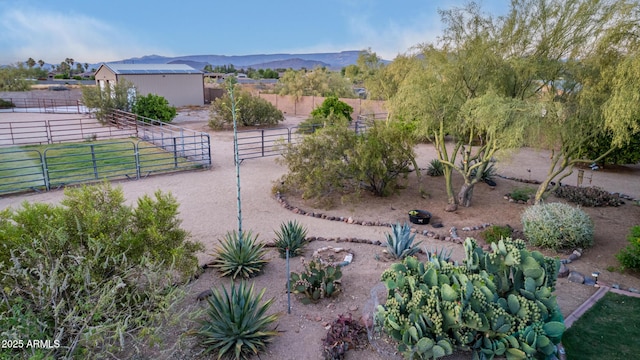 view of yard with a rural view, an outdoor structure, an exterior structure, and a mountain view