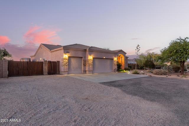 view of front of home featuring a garage, concrete driveway, stone siding, a tiled roof, and stucco siding