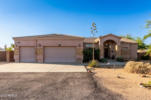 mediterranean / spanish home with an attached garage, driveway, a tiled roof, and stucco siding