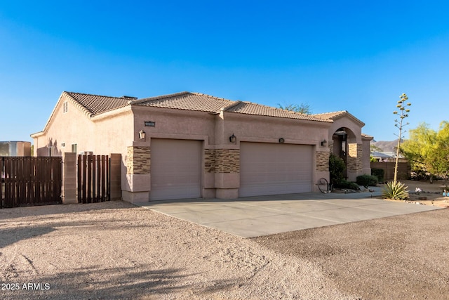 mediterranean / spanish-style house with driveway, a garage, stone siding, a tile roof, and stucco siding