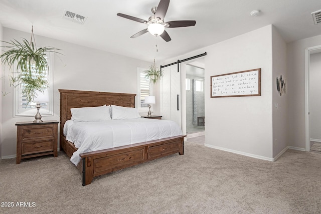 bedroom with connected bathroom, light colored carpet, a barn door, and ceiling fan