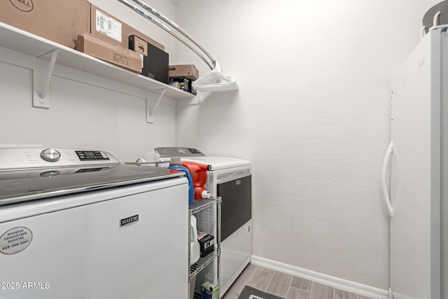 washroom with washing machine and clothes dryer and light wood-type flooring