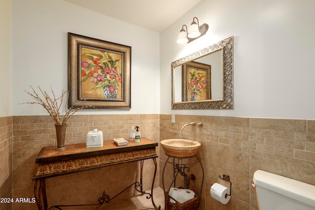 bathroom featuring toilet and tile walls