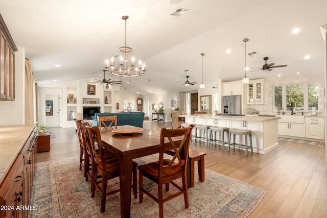 dining area featuring sink, vaulted ceiling, hardwood / wood-style flooring, built in shelves, and a notable chandelier