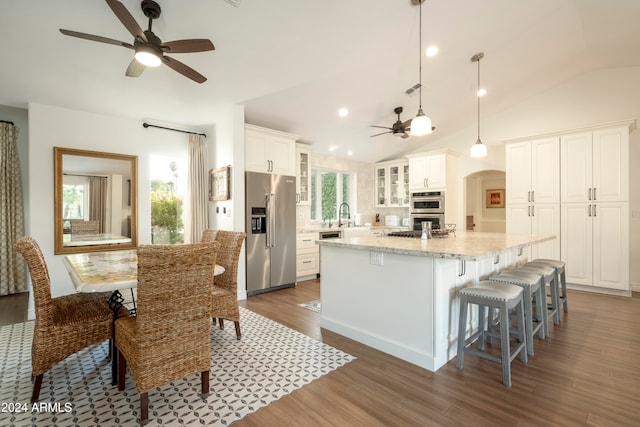 kitchen with white cabinetry, dark wood-type flooring, stainless steel appliances, lofted ceiling, and a kitchen island with sink