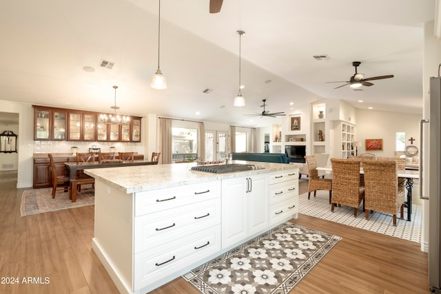 kitchen with a center island, pendant lighting, vaulted ceiling, and light wood-type flooring