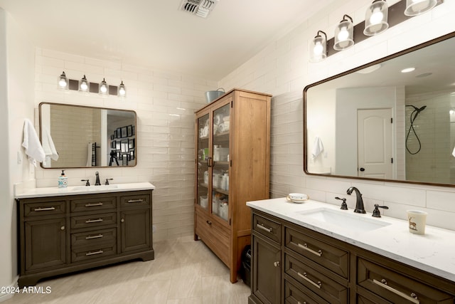 bathroom with a tile shower, backsplash, tile patterned floors, vanity, and tile walls