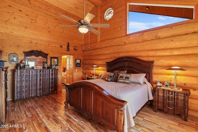 bedroom featuring wood-type flooring, log walls, and high vaulted ceiling