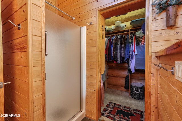 bathroom with a shower with door and wood walls