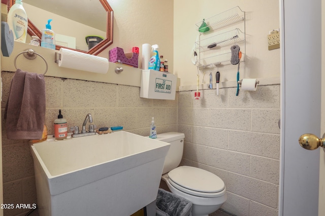 bathroom with sink, tile walls, and toilet