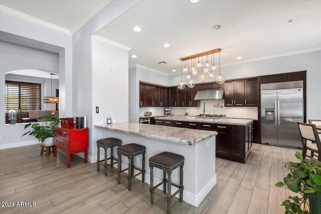 kitchen featuring stainless steel appliances, decorative light fixtures, light hardwood / wood-style flooring, and kitchen peninsula