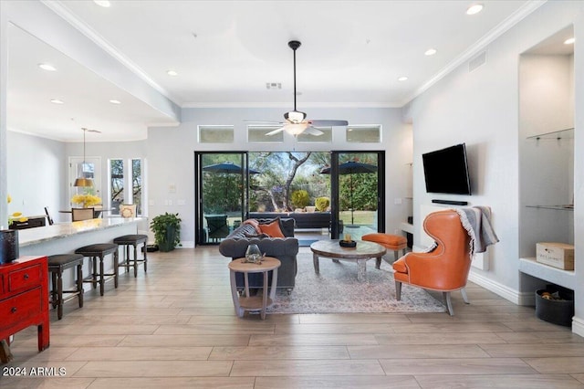 living room featuring ornamental molding, ceiling fan, and light wood-type flooring