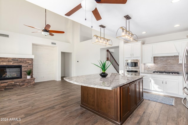 kitchen featuring white cabinetry, appliances with stainless steel finishes, an island with sink, dark wood-type flooring, and pendant lighting