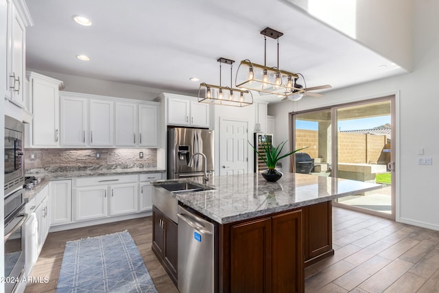 kitchen featuring an island with sink, dark hardwood / wood-style floors, white cabinetry, and appliances with stainless steel finishes