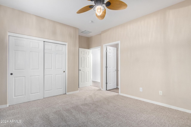 unfurnished bedroom with ceiling fan, light carpet, and a closet