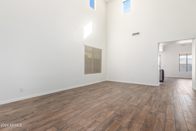 unfurnished living room featuring ceiling fan, a towering ceiling, and dark hardwood / wood-style floors