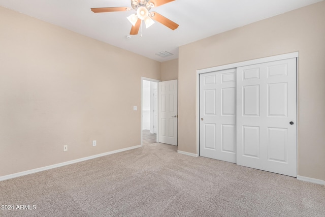 unfurnished bedroom featuring a closet, light colored carpet, and ceiling fan