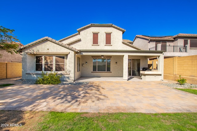 rear view of property with ceiling fan and a patio area