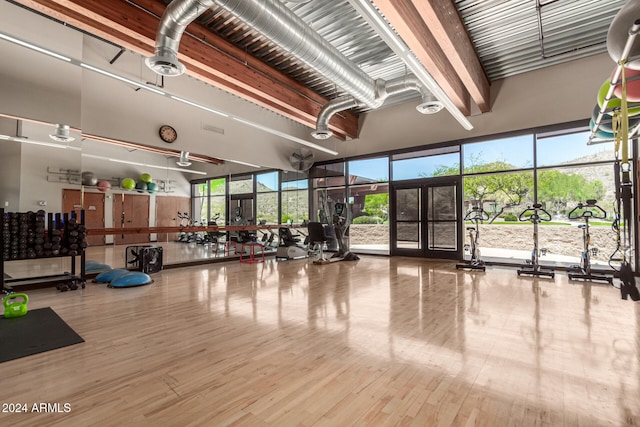 exercise room featuring a towering ceiling and wood-type flooring