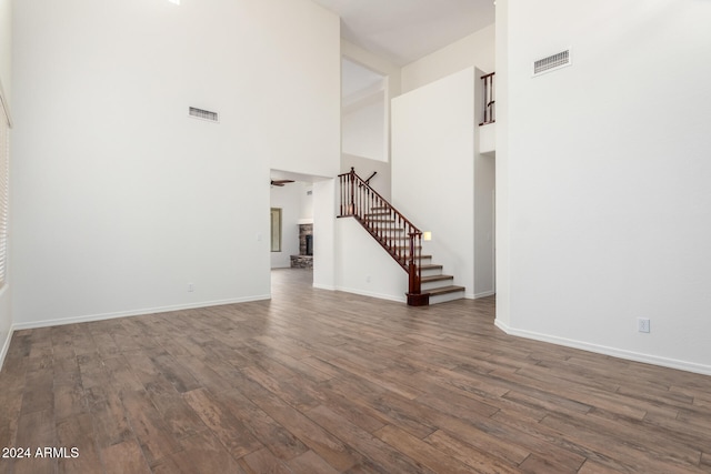 unfurnished living room featuring dark wood-type flooring and a high ceiling