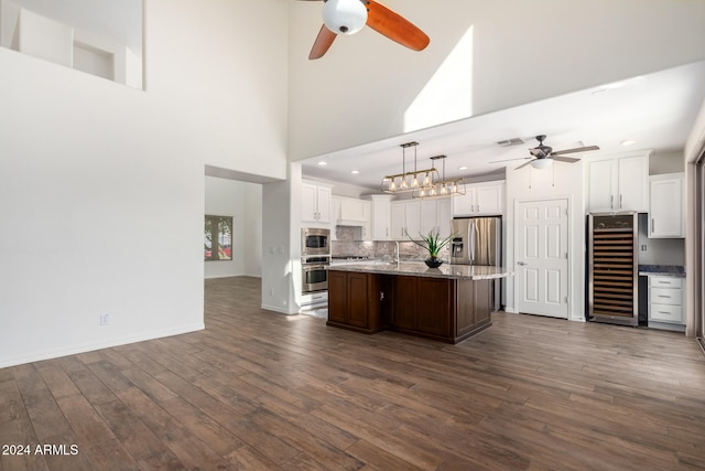 kitchen with dark wood-type flooring, beverage cooler, and a center island with sink