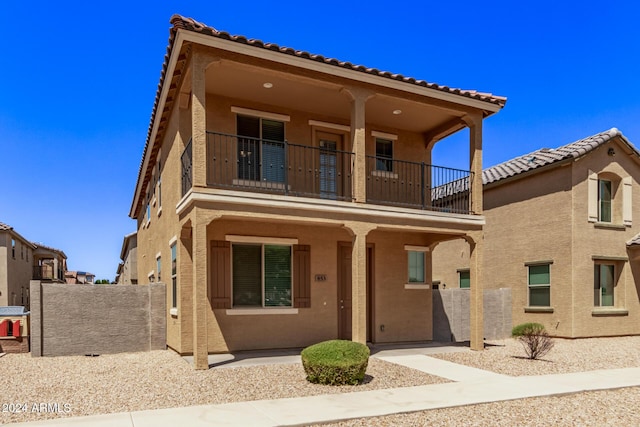 view of front of home with a porch, a balcony, and stucco siding