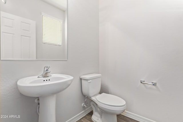 bathroom with wood finished floors, toilet, and baseboards