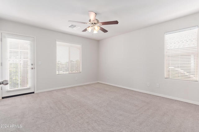 carpeted spare room featuring ceiling fan, visible vents, and baseboards