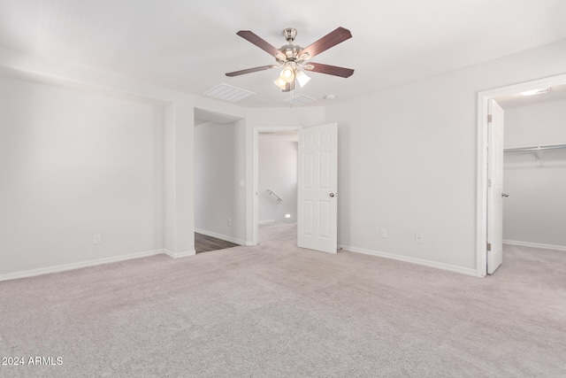 unfurnished bedroom with ceiling fan, light carpet, a closet, and a walk in closet