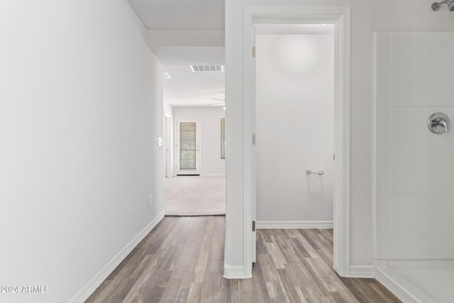 hallway featuring visible vents, baseboards, and wood finished floors