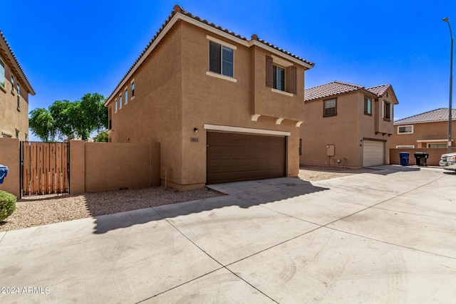 view of front of house with stucco siding, an attached garage, a gate, driveway, and a tiled roof