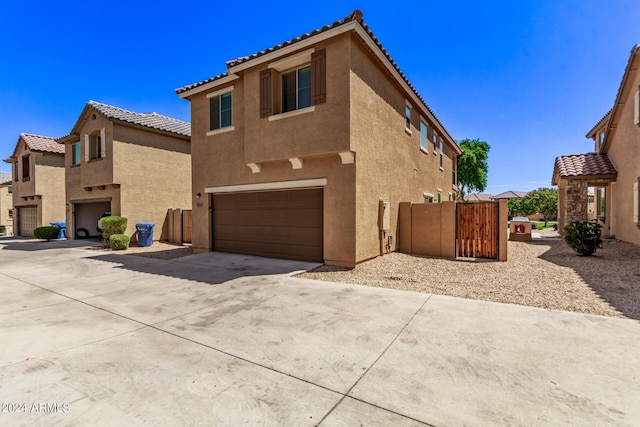 view of front of property with an attached garage, driveway, a tile roof, and stucco siding