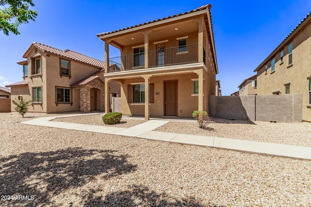 mediterranean / spanish-style house featuring fence, a balcony, and stucco siding