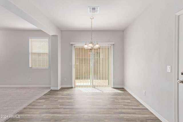 unfurnished dining area featuring a chandelier and hardwood / wood-style flooring