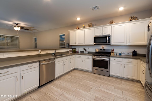 kitchen featuring white cabinetry, sink, ceiling fan, stainless steel appliances, and tasteful backsplash