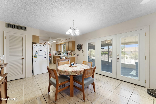 dining space with ceiling fan with notable chandelier, a textured ceiling, and light tile flooring