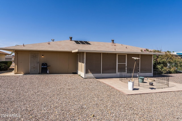 rear view of property with a patio, a sunroom, and solar panels