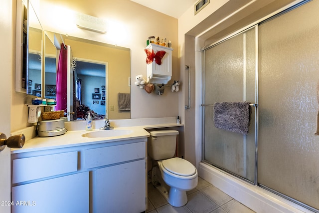 bathroom with a shower with door, toilet, vanity with extensive cabinet space, and tile flooring