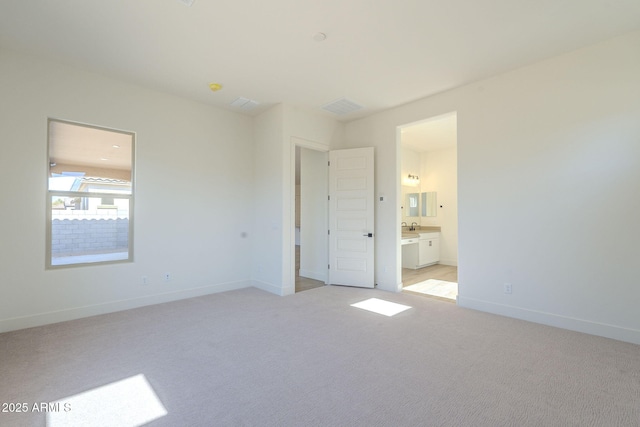 unfurnished bedroom featuring connected bathroom, sink, and light carpet