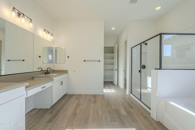 bathroom featuring hardwood / wood-style flooring, vanity, and plus walk in shower