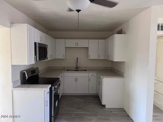 kitchen featuring appliances with stainless steel finishes, dark wood-type flooring, sink, and white cabinets