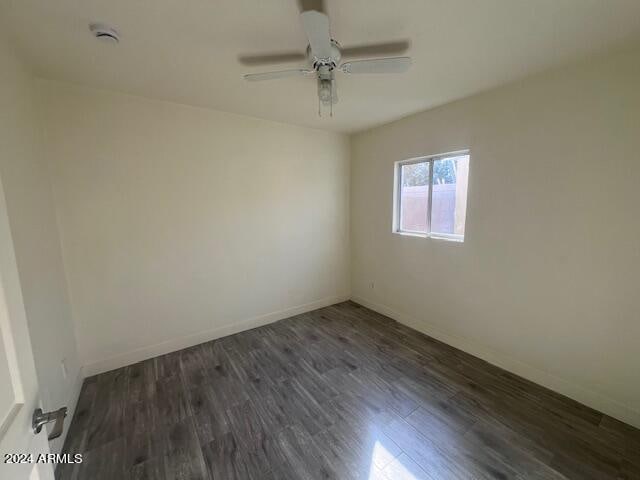 empty room with ceiling fan and dark hardwood / wood-style flooring